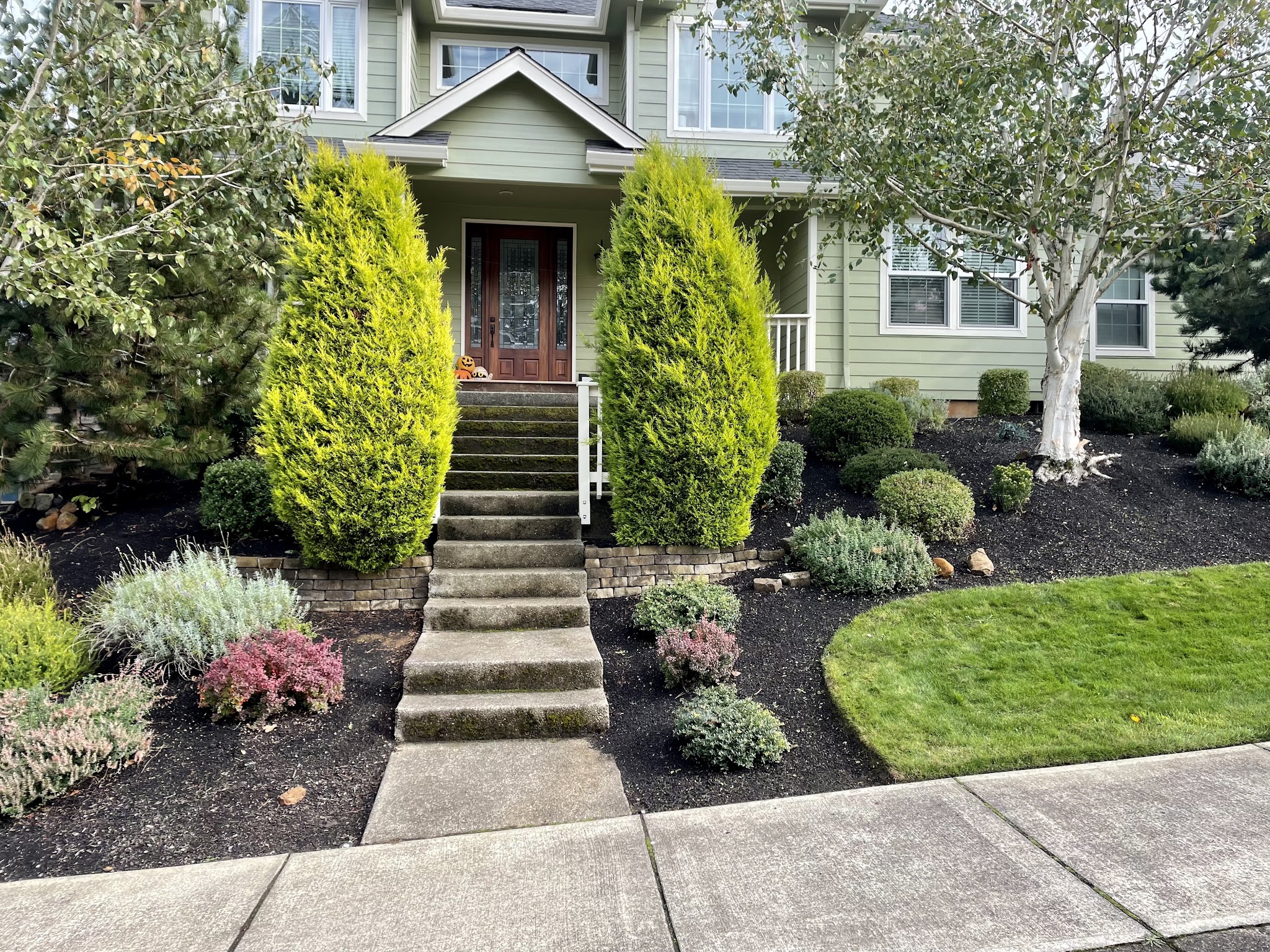 Landscaped front entry with mulch beds and trimmed shrubs by Mid Valley Lawn Care